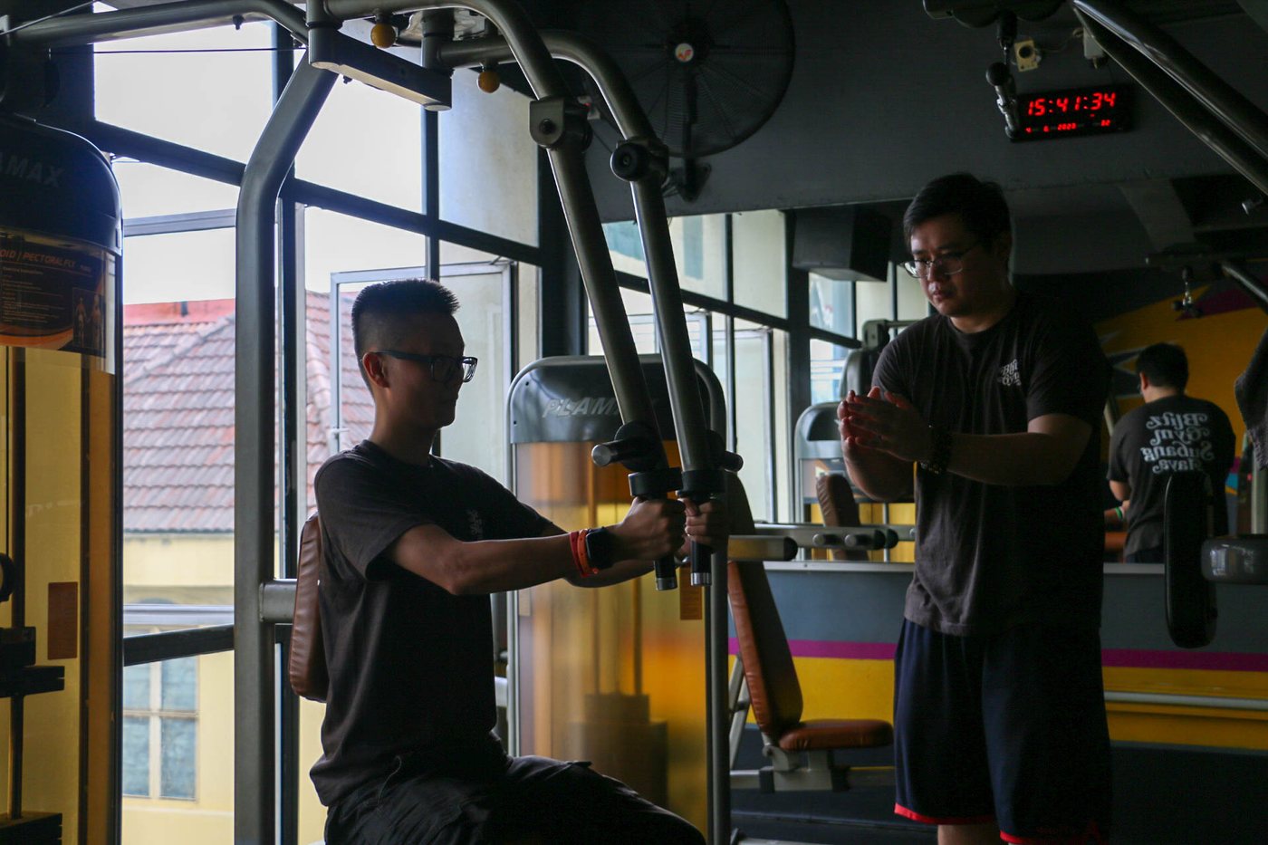Member training with a trainer on the cable machine at Blitz Gym SS15